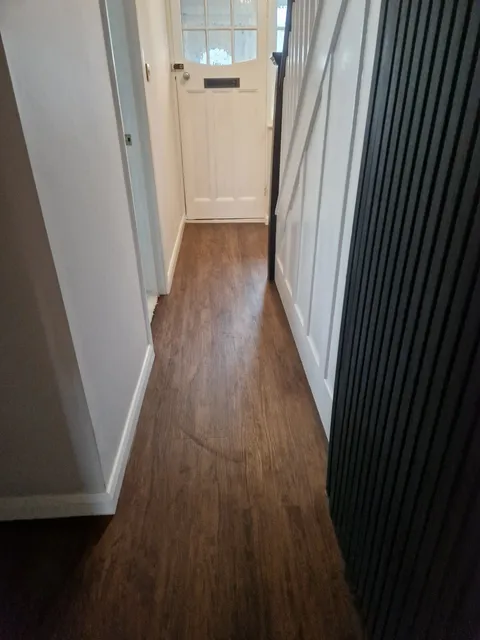Dark wood-effect LVT plank flooring running down a hallway to the front door