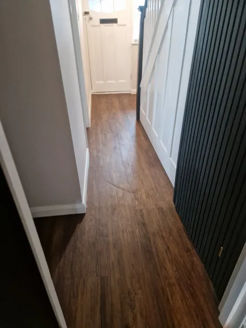 Rich dark wood-effect LVT planks in a hallway beside a panelled radiator