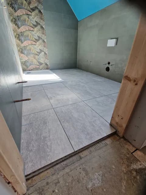 Grey large-format square floor tiles laid across a tiled room with tropical feature panel