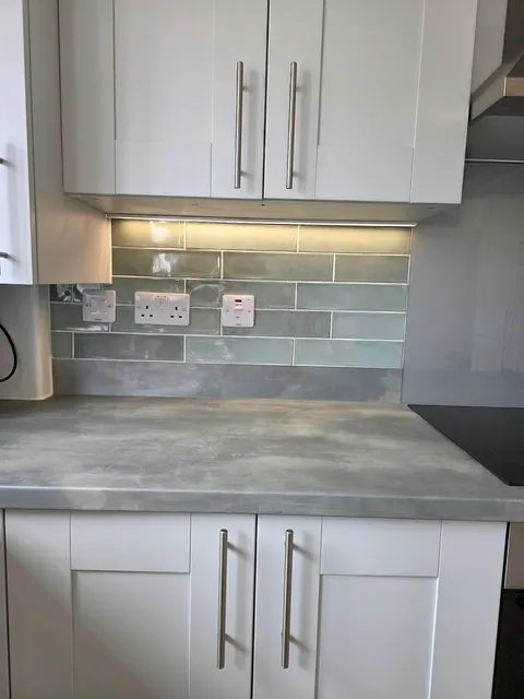 Sage green gloss metro tile splashback with cream shaker units and concrete-effect worktop