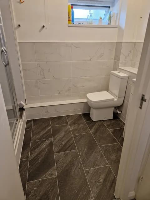 White marble-effect wall tiles with toilet and basin over slate-effect rectangular floor tiles