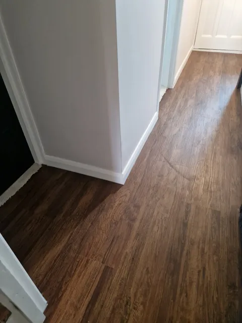 Warm dark wood-effect LVT plank flooring along a hallway